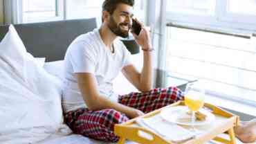A man using a phone while having breakfast in bed