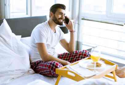 A man using a phone while having breakfast in bed